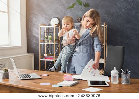 Happy Mother Working At Office With Her Baby. Young Woman Talking On Phone And Reading Documents Whi