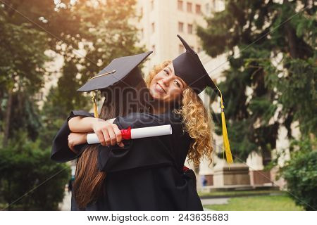 Pair Of Students Hugging On Their Graduation Day At University, Having Fun And Saying Good Bye To Fr