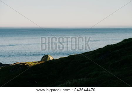 Tent on the mountain ridge above Ramberg. lit by the midnight sun and looking onto the sea, lofoten, Northern Norway