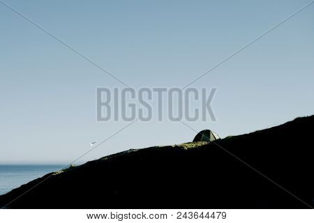 Tent on the mountain ridge above Ramberg. lit by the midnight sun and looking onto the sea, lofoten, Northern Norway