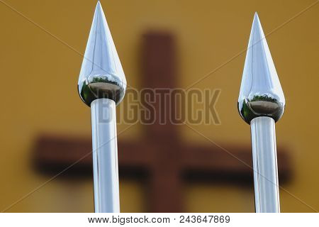 Iron Spearhead Fence With Cross In Background.