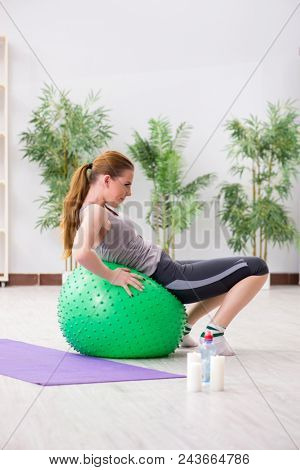 Young woman exercising with stability ball in gym