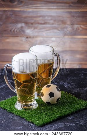 Photo Of Two Beer Mugs, Green Grass With Soccer Ball On Wooden Background