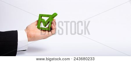 A Man Who Is Unemployed In A Business Suit Is Holding A Wooden Box. A Tick In The Box. The Hand Hold