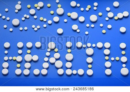Yellow And White Tablets Scattered On A Blue Medical Table, Background, Inscription Health