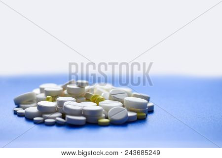 Yellow And White Tablets Scattered On A Blue Medical Table, Background, Copy Space