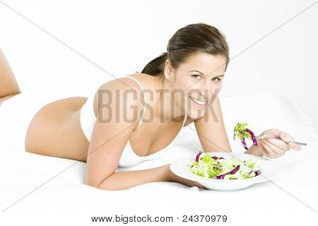 liggende kvinde spiser salat