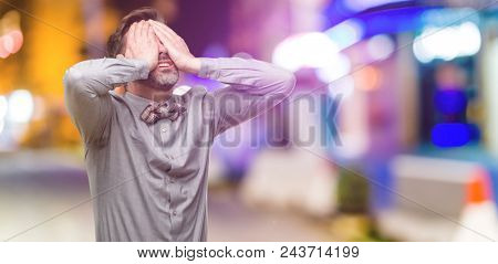 Middle age man, with beard and bow tie stressful keeping hands on head, tired and frustrated at night club
