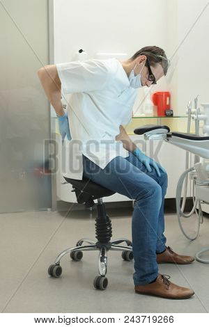 Dentist with lower back pain at work in his office in his office