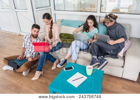 Happy young people laughing while sharing a collaborative office space as co-workers in a modern hub with WI-FI wireless network for digital nomads
