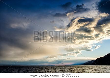 Sunset Over Stormy Clouds Across The Water Reflecting Dark And Looming Dramatic Sky Moody Feeling Of