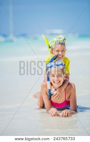 Brother And Sister In Scuba Masks Playing And Having Fun On The Beach During The Hot Summer Vacation