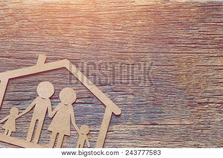 Paper Cut Of A Family And House On Wooden Table. Save And Investment Money For Prepare In The Future