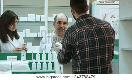Attractive Woman And Senior Pharmacist Listening To Male Customer Dissapointed