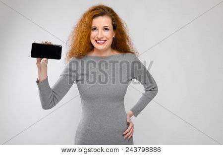 Charming Young Girl With Red Hair. A Young Girl In A Gray Sweater. Young Girl On A Gray Background.