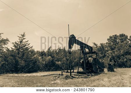 Vintage Tone Working Pump Jack Pumping Crude Oil At Oil Drilling Site In Rural Usa