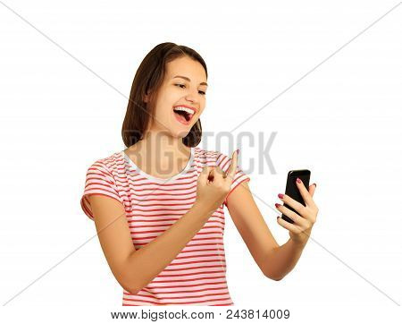 The Spiteful Smiling Girl Shows The Middle Finger In The Phone. Fuck You Sign. Emotional Girl Isolat