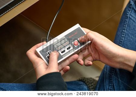 BUDAPEST, HUNGARY - FEBRUARY 17, 2018: Playing the classic Nintendo NES console from the 80s, controller closeup