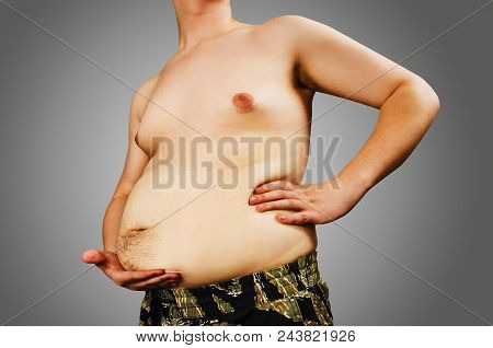 Torso Of Young Fat Man Holding His Belly On Gray Background. Half-profile