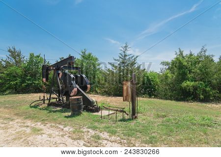 Working Pump Jack Pumping Crude Oil At Oil Drilling Site In Rural Usa