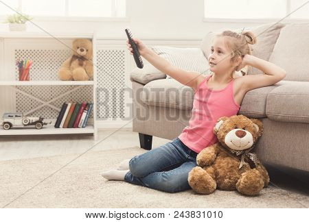 Little Casual Girl Watching Tv At Home. Female Kid Sitting On Floor Carpet With Her Toy Friend Teddy
