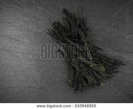 Heap Of Dry Wakame Seaweed On Black Stone Background. Healthy Algae Food With Place For Text