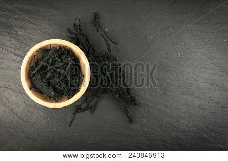 Heap Of Dry Wakame Seaweed On Black Stone Background. Healthy Algae Food With Place For Text