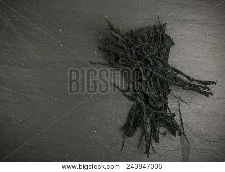 Heap Of Dry Wakame Seaweed On Black Stone Background. Healthy Algae Food With Place For Text