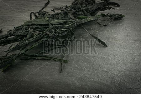 Heap Of Dry Wakame Seaweed On Black Stone Background. Healthy Algae Food With Place For Text