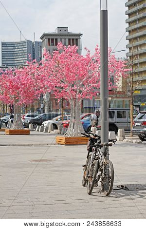 Moscow, Russia - April 30, 2018: Parked Bicycles On The Background Of Artificial Pink Trees On The N