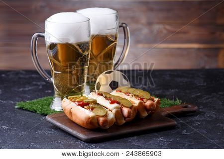 Photo Of Two Mugs Of Foam Beer, Green Grass With Football, Hotdogs On Wooden Board