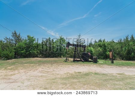 Working Pump Jack Pumping Crude Oil At Oil Drilling Site In Rural Usa
