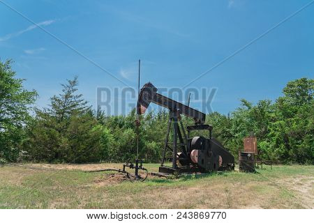 Working Pump Jack Pumping Crude Oil At Oil Drilling Site In Rural Usa