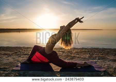 Silhouette Woman On The Beach At Sunset Doing Yoga Asana. Morning Natural Stretch Warm-up Training