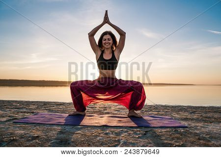 Silhouette Woman On The Beach At Sunset Doing Yoga Asana. Morning Natural Stretch Warm-up Training