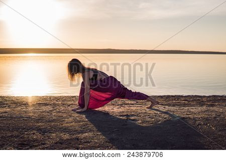 Silhouette Woman On The Beach At Sunset Doing Yoga Asana. Morning Natural Stretch Warm-up Training