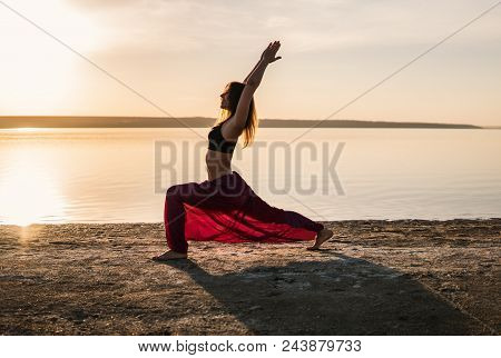 Silhouette Woman On The Beach At Sunset Doing Yoga Asana. Morning Natural Stretch Warm-up Training