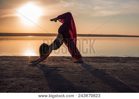Silhouette Woman On The Beach At Sunset Doing Yoga Asana. Morning Natural Stretch Warm-up Training