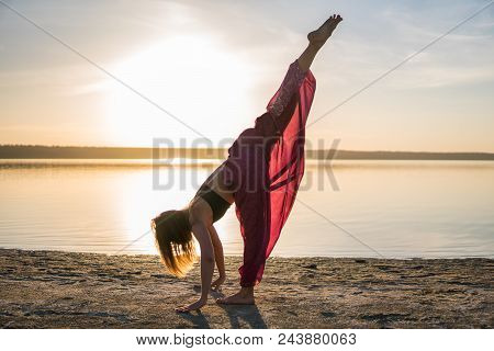 Silhouette Woman On The Beach At Sunset Doing Yoga Asana. Morning Natural Stretch Warm-up Training