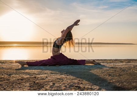 Silhouette Woman On The Beach At Sunset Doing Yoga Asana. Morning Natural Stretch Warm-up Training