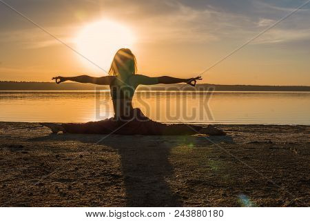 Silhouette Woman On The Beach At Sunset Doing Yoga Asana. Morning Natural Stretch Warm-up Training