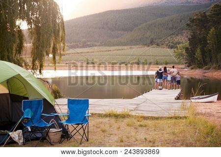 Multi Generation Family On Camping Trip Stand On Jetty By Lake