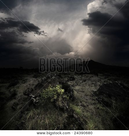 Nubi scure sopra valle vulcanica con erba e rocce. Monte Agung di Bali. Indonesia