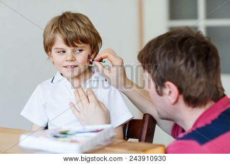 Young Dad Painting Flag On Face Of Little Son For Football Or Soccer Game. Happy Excited Preschool K
