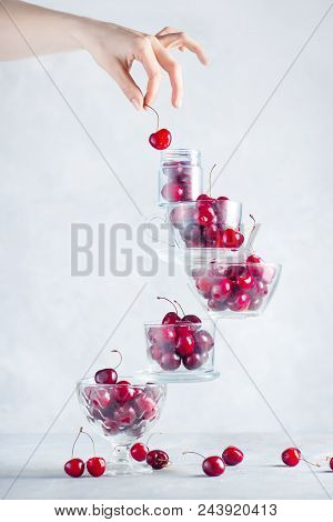Cherry On Top Of A Balancing Stack Of Bowls And Cups Filled With Berries. Final Touch Concept On A W