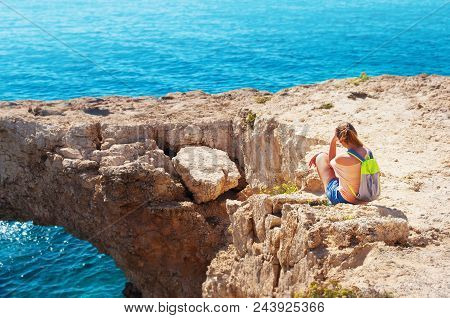 One Caucasian Girl Sitting On The Edge Of The Cliff Leaning Against Her Hand With Her Back Turned Aw