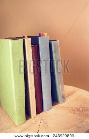 Retro Toned Image Of Vertical Stack Of Old Books On Wooden Saw Cut. Back To School Concept.