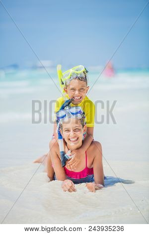 Brother And Sister In Scuba Masks Playing And Having Fun On The Beach During The Hot Summer Vacation
