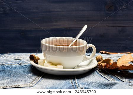 Mug Filled With Black Brewed Tea, Spoon And Autumn Fallen Leaves On Denim Background. Autumn Drink C