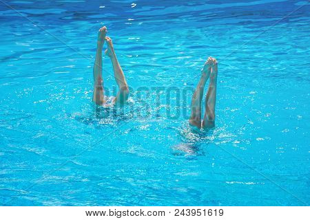 Synchronised Swimming. Beautiful Lean Female Legs In The Water Of A Swimming Pool. Concept Of Beauty